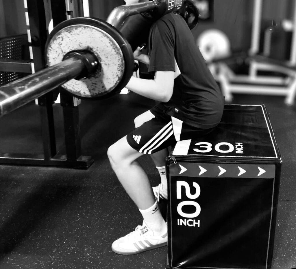 Soccer athlete performing box squat to minimize knee pain